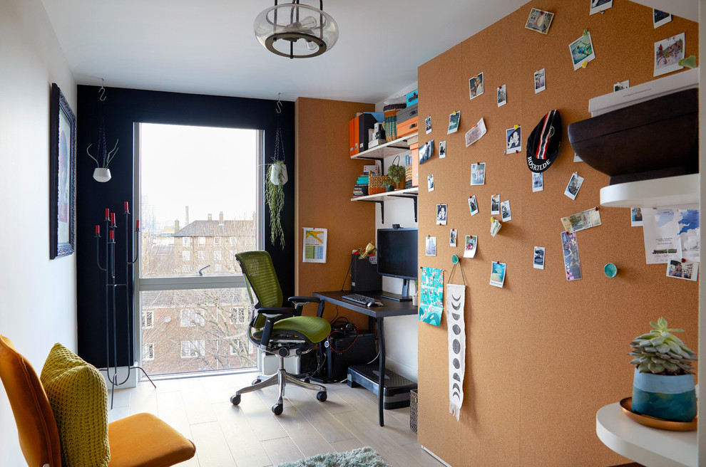 Kleines Modernes Arbeitszimmer ohne Kamin mit Arbeitsplatz, schwarzer Wandfarbe, hellem Holzboden, freistehendem Schreibtisch und grauem Boden in London