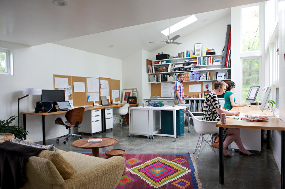 Idee per un grande atelier minimal con pareti bianche, pavimento in cemento, scrivania autoportante e pavimento grigio