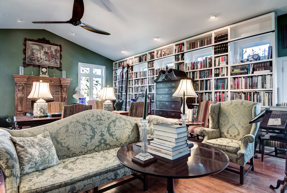Großes Klassisches Lesezimmer mit grüner Wandfarbe, braunem Holzboden, Kamin, Kaminumrandung aus Holz, freistehendem Schreibtisch und braunem Boden in Chicago