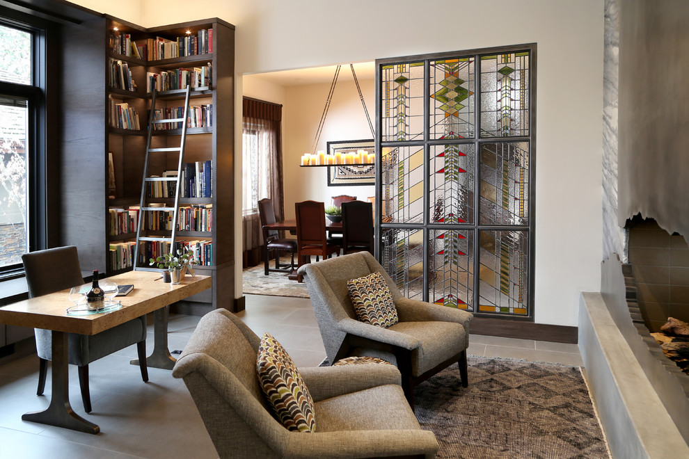 Источник вдохновения для домашнего уюта: домашняя библиотека среднего размера в современном стиле с белыми стенами, полом из керамической плитки, двусторонним камином, фасадом камина из металла, отдельно стоящим рабочим столом и серым полом