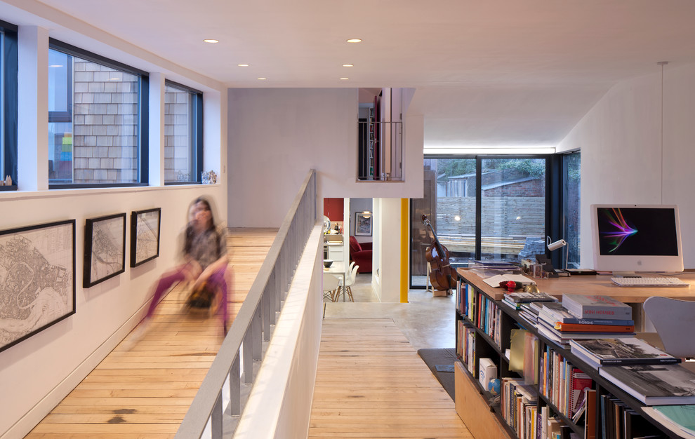 Réalisation d'un bureau design avec un mur blanc, parquet clair et une bibliothèque ou un coin lecture.