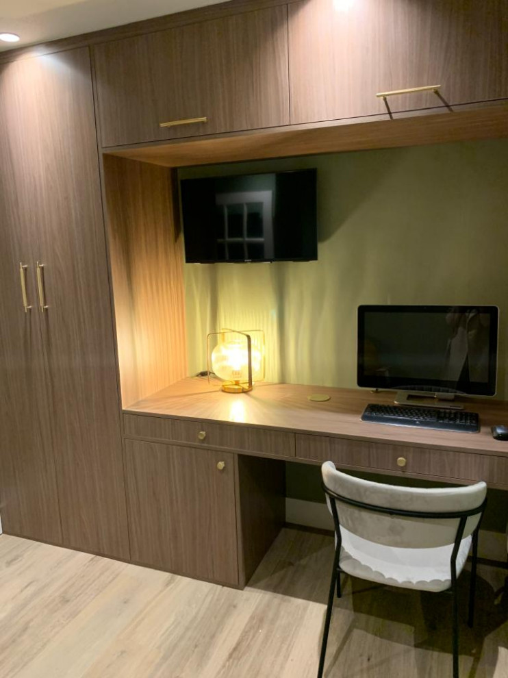 Idéer för små funkis arbetsrum, med ett bibliotek, gröna väggar, laminatgolv och ett inbyggt skrivbord