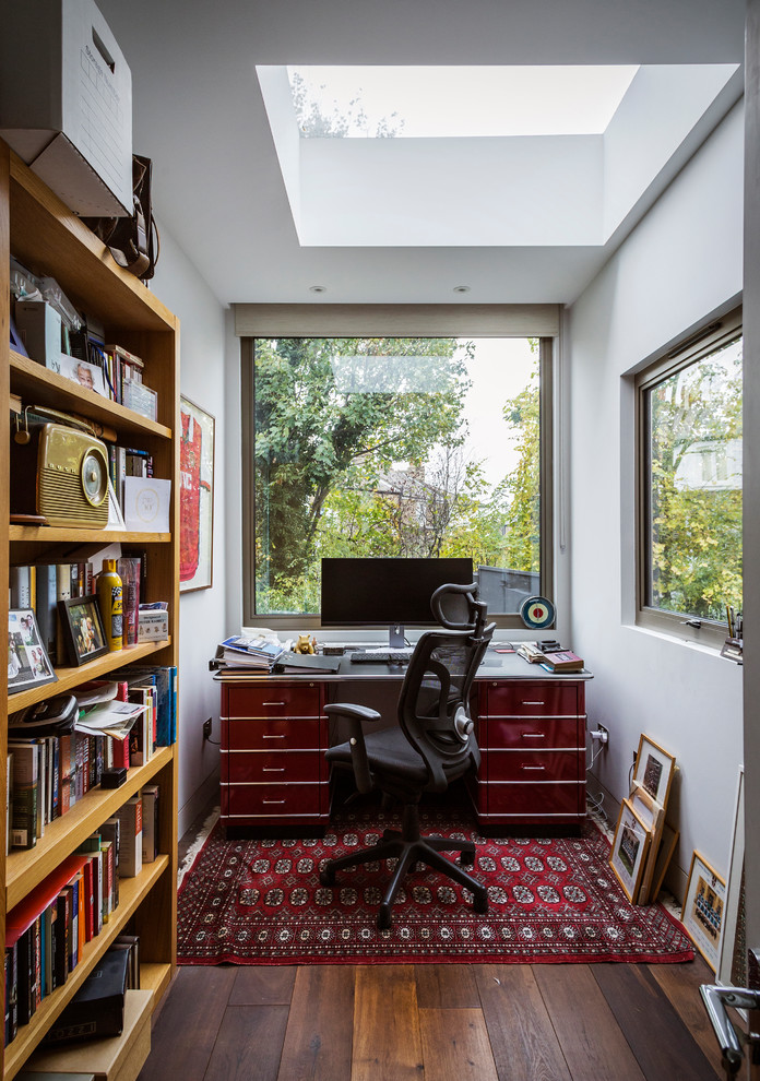 This is an example of a small traditional study in London with white walls, a freestanding desk, brown floors and medium hardwood flooring.