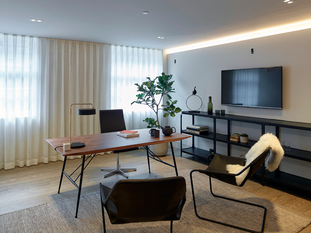 Mittelgroßes Modernes Arbeitszimmer mit Arbeitsplatz, grauer Wandfarbe, hellem Holzboden, freistehendem Schreibtisch und braunem Boden in London