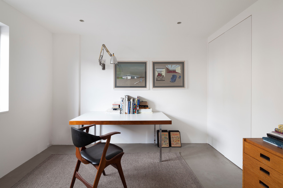 Ejemplo de despacho contemporáneo sin chimenea con paredes blancas, suelo de cemento y escritorio independiente