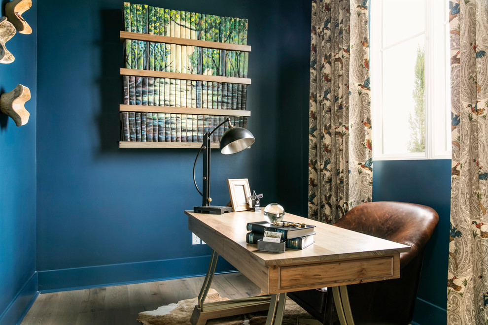 Inspiration för små rustika hemmabibliotek, med blå väggar, ljust trägolv, ett fristående skrivbord och beiget golv