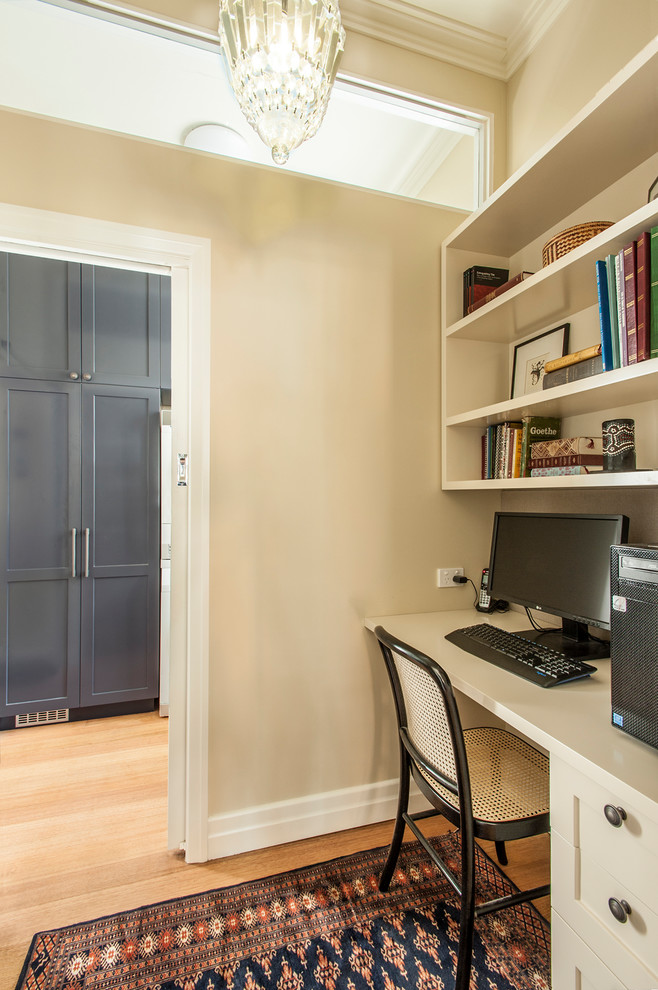Cette photo montre un petit bureau craftsman avec un mur beige, un sol en bois brun et un bureau indépendant.