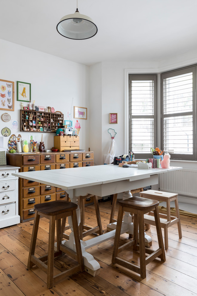 Diseño de sala de manualidades campestre con paredes blancas, suelo de madera en tonos medios, escritorio independiente y suelo marrón