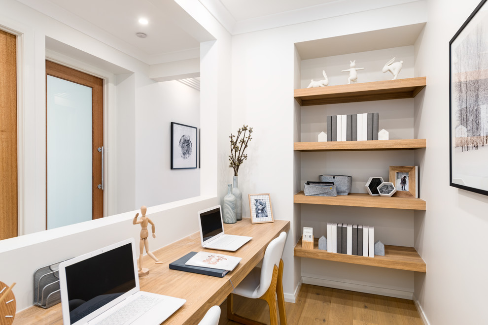 Idéer för att renovera ett litet skandinaviskt hemmabibliotek, med vita väggar, ett inbyggt skrivbord och brunt golv