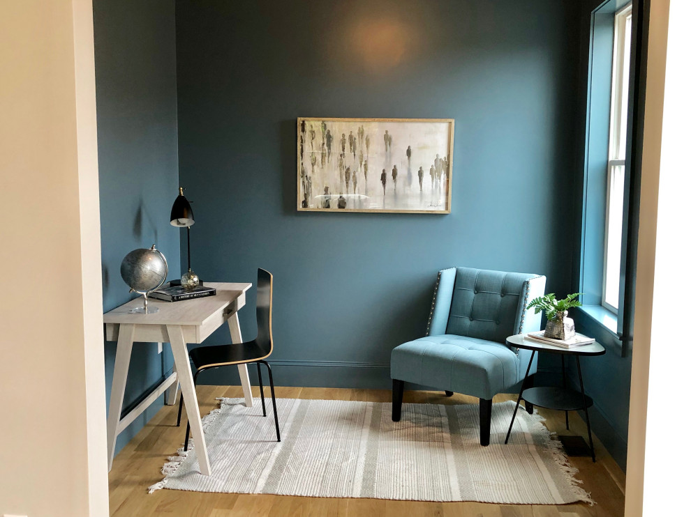 Kleines Modernes Arbeitszimmer ohne Kamin mit blauer Wandfarbe, hellem Holzboden, freistehendem Schreibtisch und beigem Boden in Boston