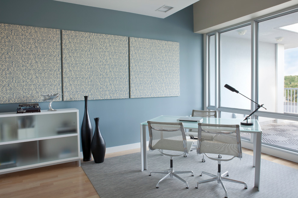 Large contemporary study in New York with blue walls, light hardwood flooring, no fireplace and a freestanding desk.