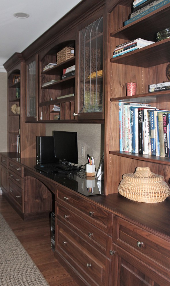 Foto di un grande studio classico con libreria, pareti beige, pavimento in legno massello medio, scrivania incassata e pavimento marrone