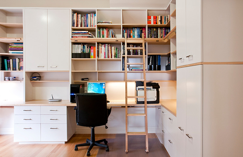 Idee per un grande ufficio minimal con pareti bianche, parquet chiaro, scrivania incassata e nessun camino
