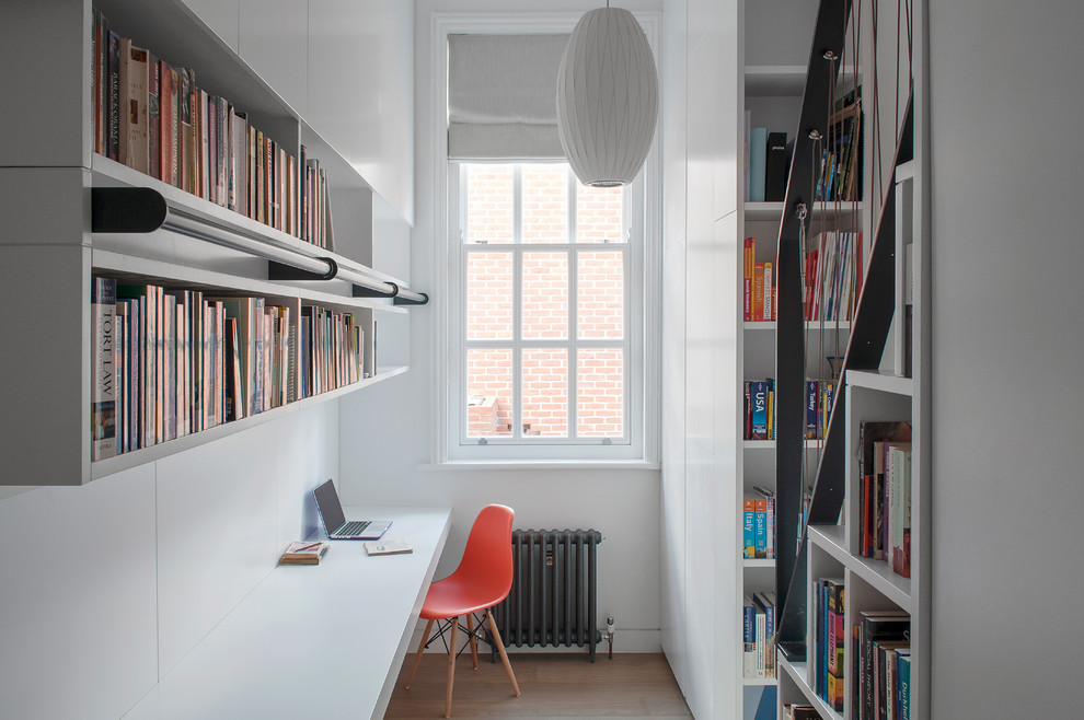 Cette image montre un bureau design avec une bibliothèque ou un coin lecture, un mur blanc, un sol en bois brun, un bureau intégré et un sol marron.