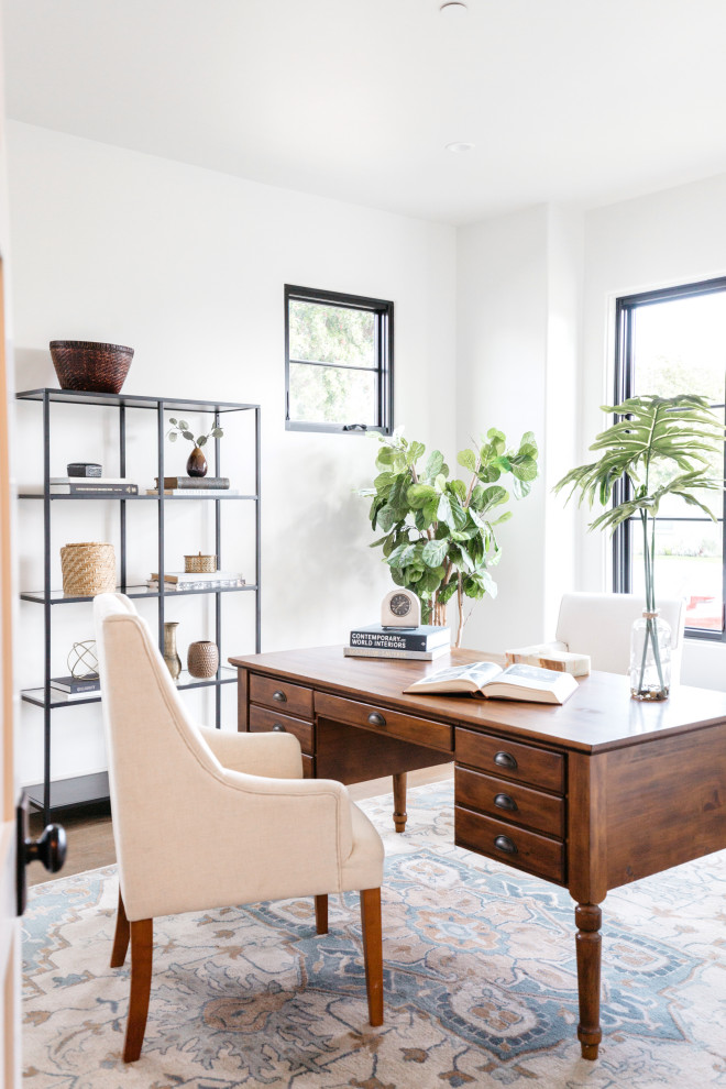 Inspiration for a mediterranean home office in Los Angeles with white walls, medium hardwood flooring, a freestanding desk and brown floors.