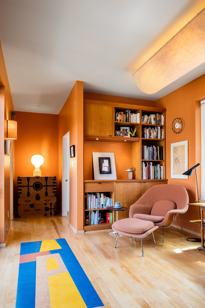 На фото: маленький домашняя библиотека в стиле модернизм с оранжевыми стенами и светлым паркетным полом для на участке и в саду с