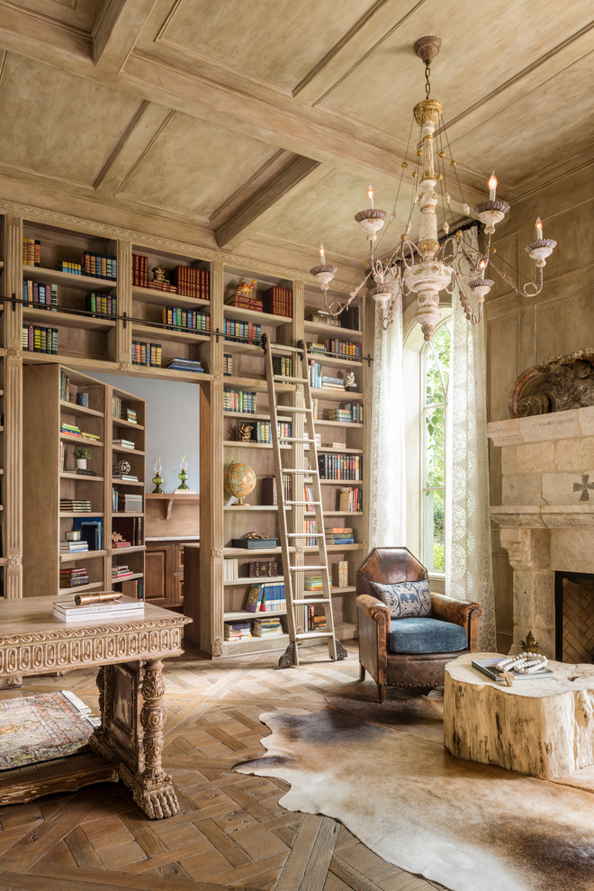 ヒューストンにある地中海スタイルのおしゃれなホームオフィス・書斎 (無垢フローリング、標準型暖炉、自立型机、茶色い床) の写真