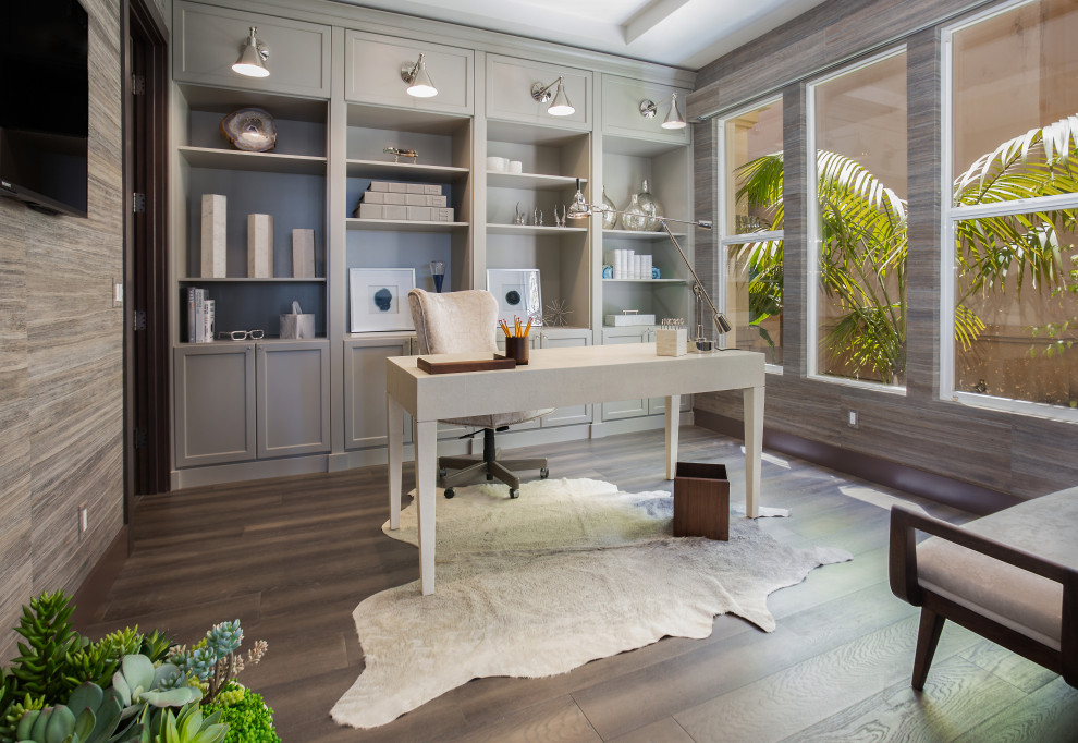 Diseño de despacho actual con paredes grises, suelo de madera oscura, escritorio independiente y suelo marrón