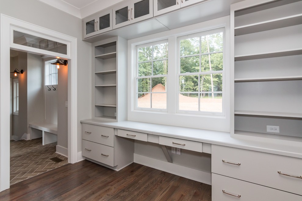 Diseño de despacho de estilo de casa de campo grande con paredes grises, suelo de madera en tonos medios y escritorio empotrado