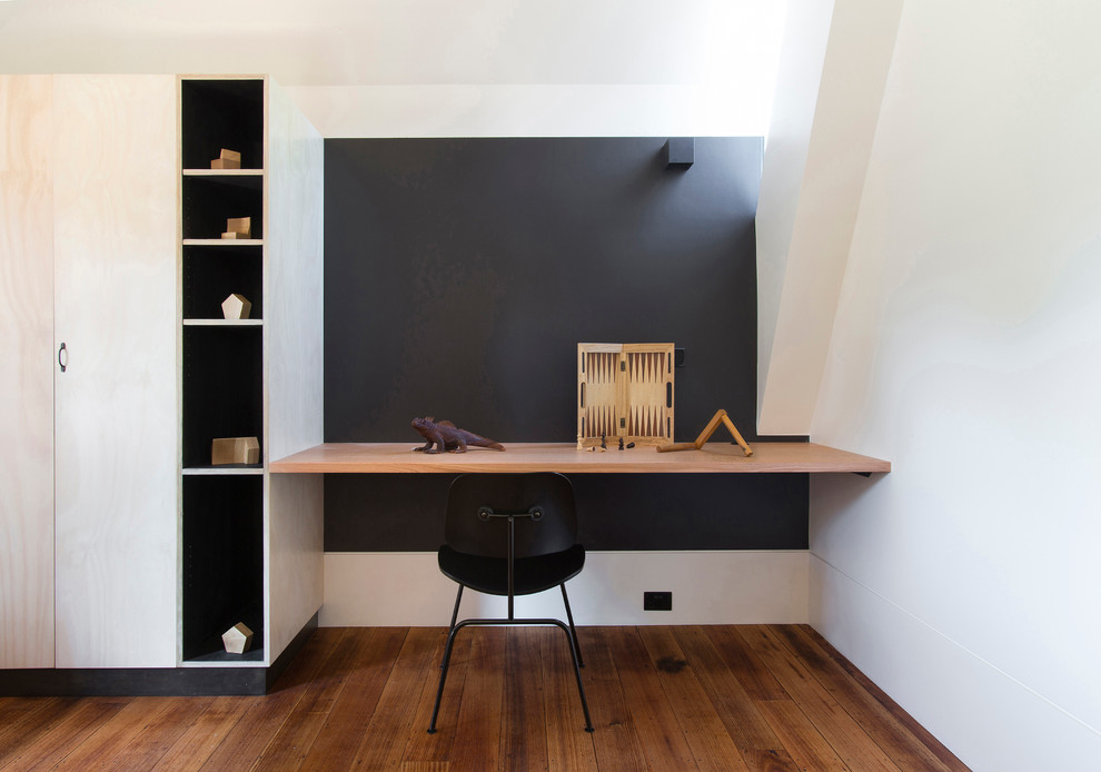 Cette image montre un bureau design avec un mur noir, un sol en bois brun, un bureau intégré, aucune cheminée et un sol marron.