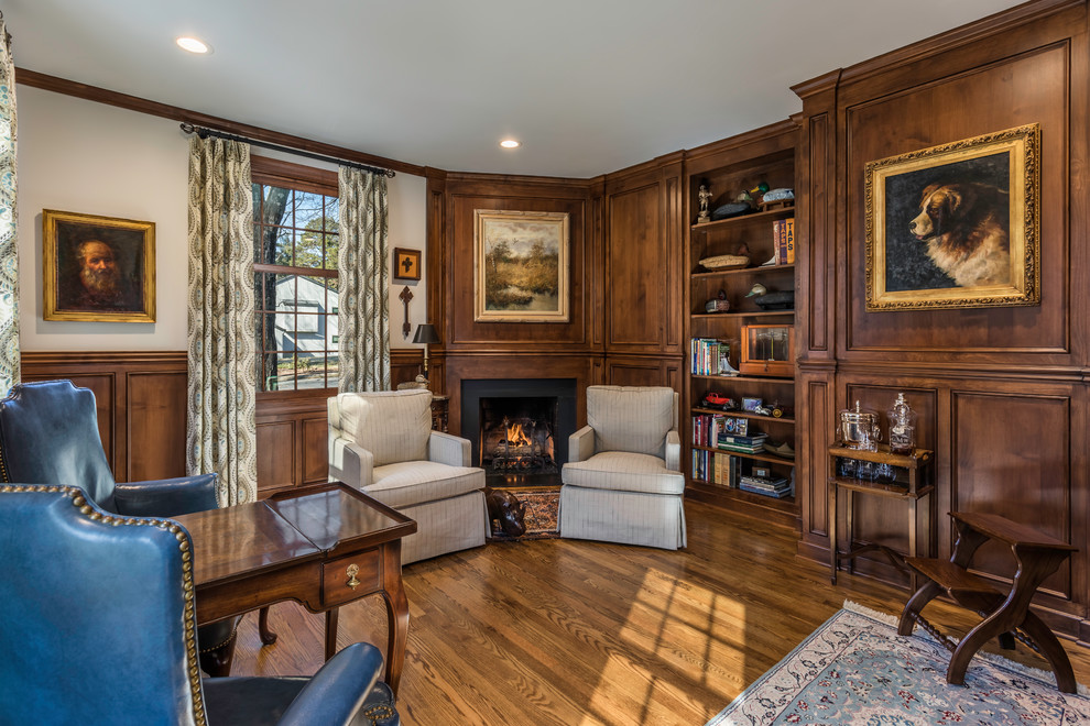 Large classic study in Other with beige walls, medium hardwood flooring, a standard fireplace, a stone fireplace surround, a freestanding desk and brown floors.