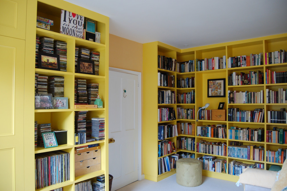 Idee per un soggiorno design di medie dimensioni e chiuso con libreria, pareti gialle, moquette e pavimento beige