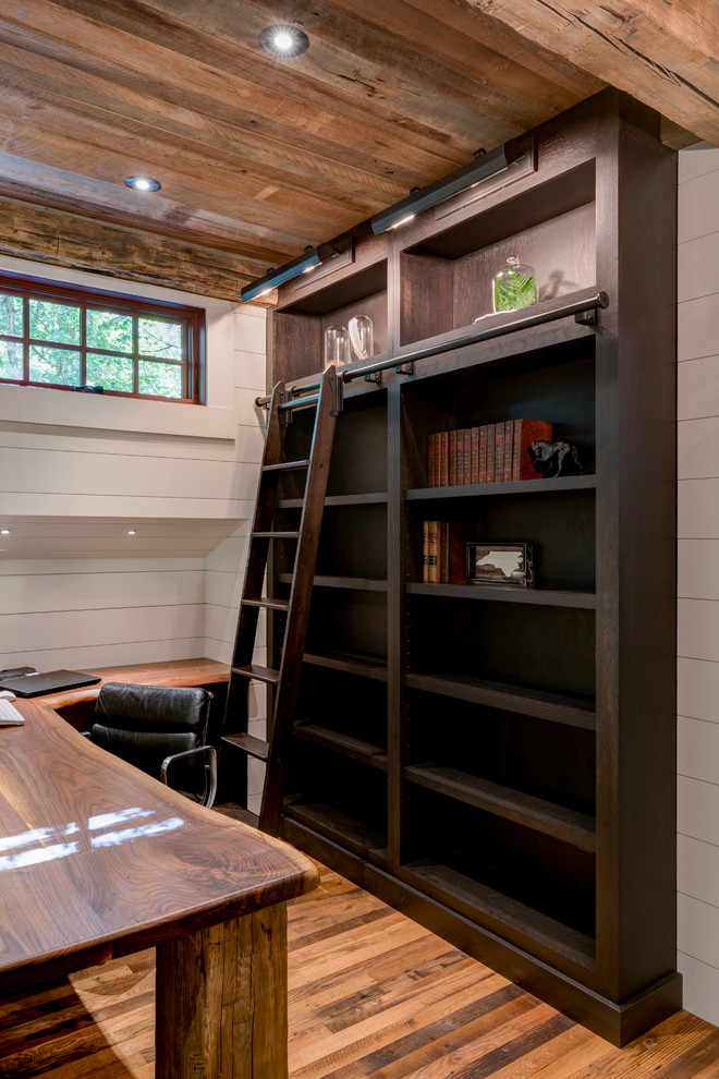 Ejemplo de despacho rústico de tamaño medio con biblioteca, suelo de madera en tonos medios y escritorio empotrado