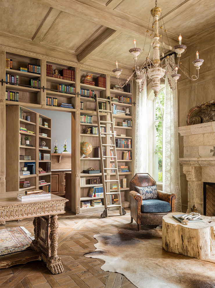 Exemple d'un bureau méditerranéen avec une bibliothèque ou un coin lecture, un mur beige, un sol en bois brun, une cheminée standard, un manteau de cheminée en pierre et un bureau indépendant.
