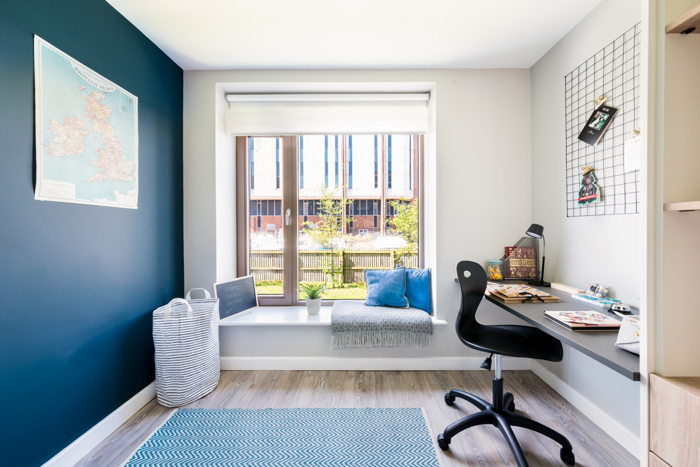 Cette image montre un bureau design avec un mur bleu, un bureau intégré et un sol marron.