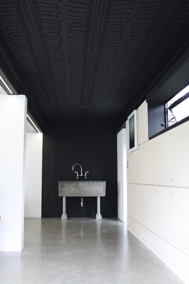 Esempio di un piccolo atelier industriale con pareti nere e pavimento in cemento