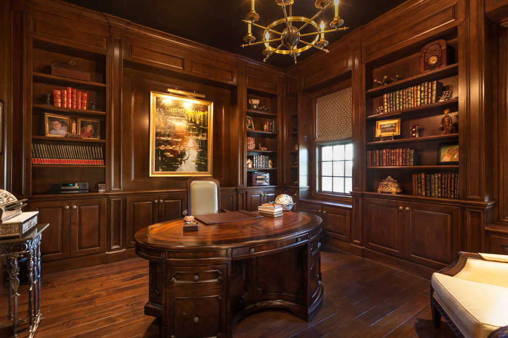 Mittelgroßes Klassisches Arbeitszimmer ohne Kamin mit Arbeitsplatz, brauner Wandfarbe, dunklem Holzboden und freistehendem Schreibtisch in Houston
