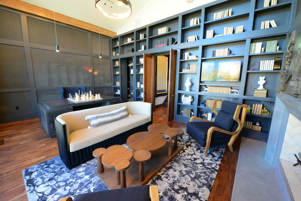 Diseño de despacho minimalista grande con paredes grises, suelo de madera en tonos medios, todas las chimeneas, marco de chimenea de hormigón, escritorio independiente y suelo marrón