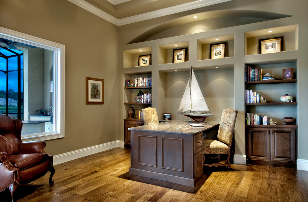 Modelo de despacho clásico con suelo de madera en tonos medios, escritorio empotrado y paredes verdes