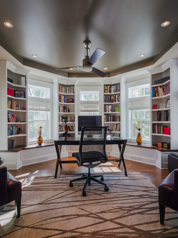 Photo of a classic study in Chicago with dark hardwood flooring, a freestanding desk and white walls.