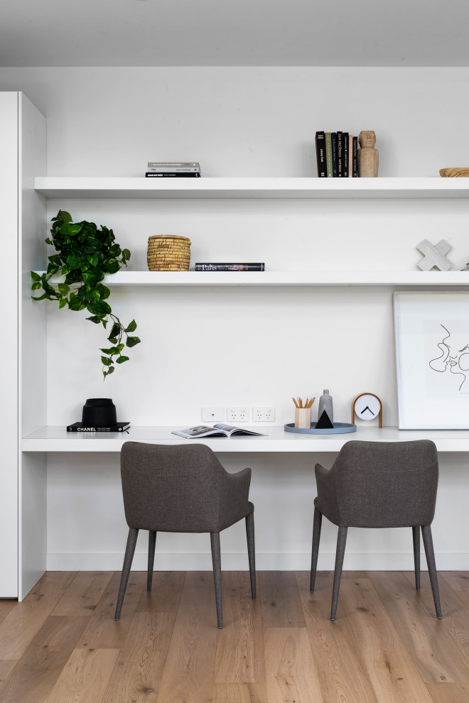 Idée de décoration pour un bureau design de taille moyenne avec un mur blanc, un bureau intégré, un sol en bois brun et un sol beige.
