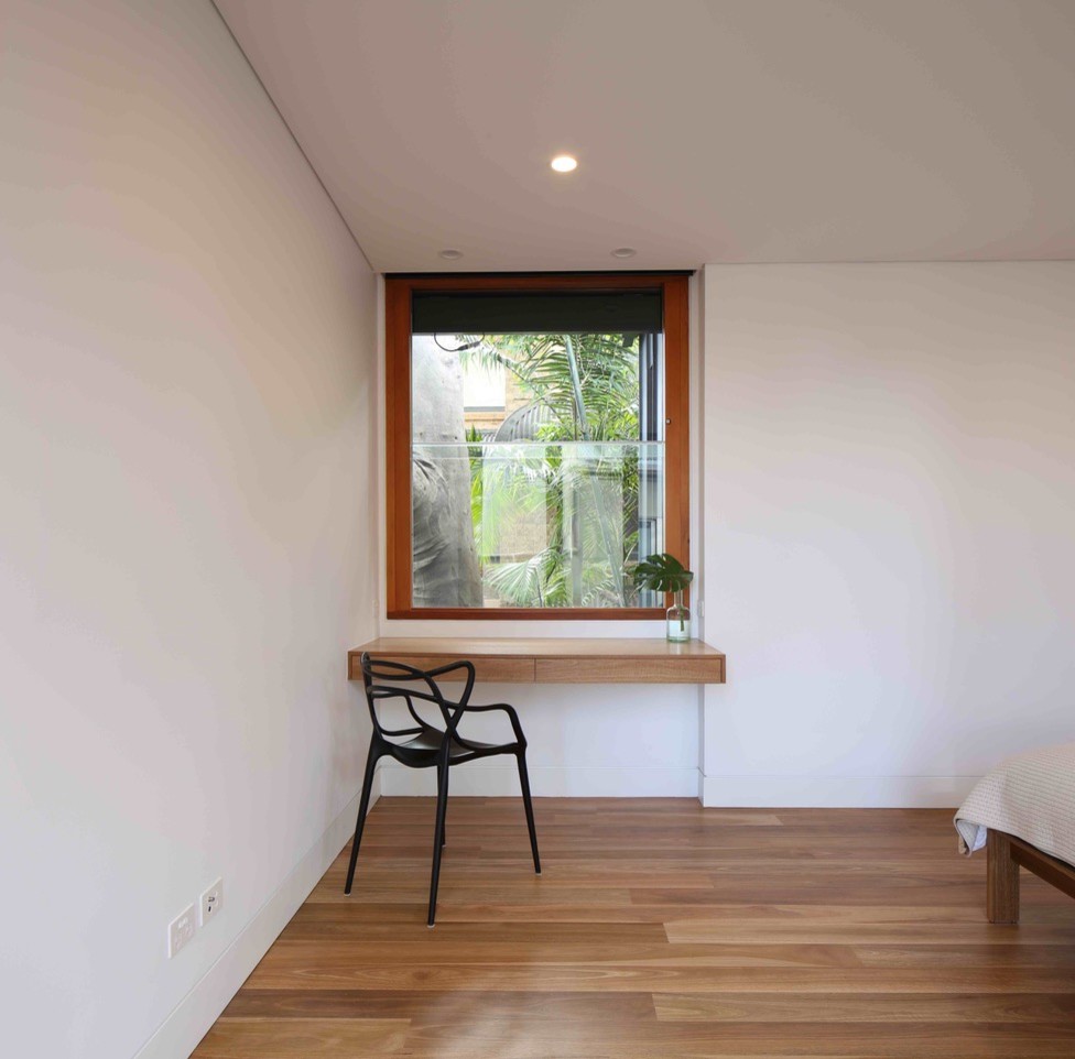 Ejemplo de despacho contemporáneo pequeño con paredes blancas, suelo de madera clara, escritorio empotrado y suelo marrón