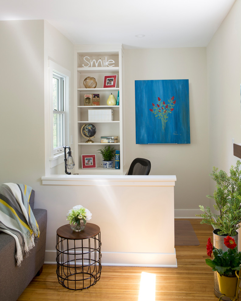 Kleines Klassisches Lesezimmer mit weißer Wandfarbe, braunem Holzboden, Kamin, Kaminumrandung aus Stein, Einbau-Schreibtisch und braunem Boden in New York