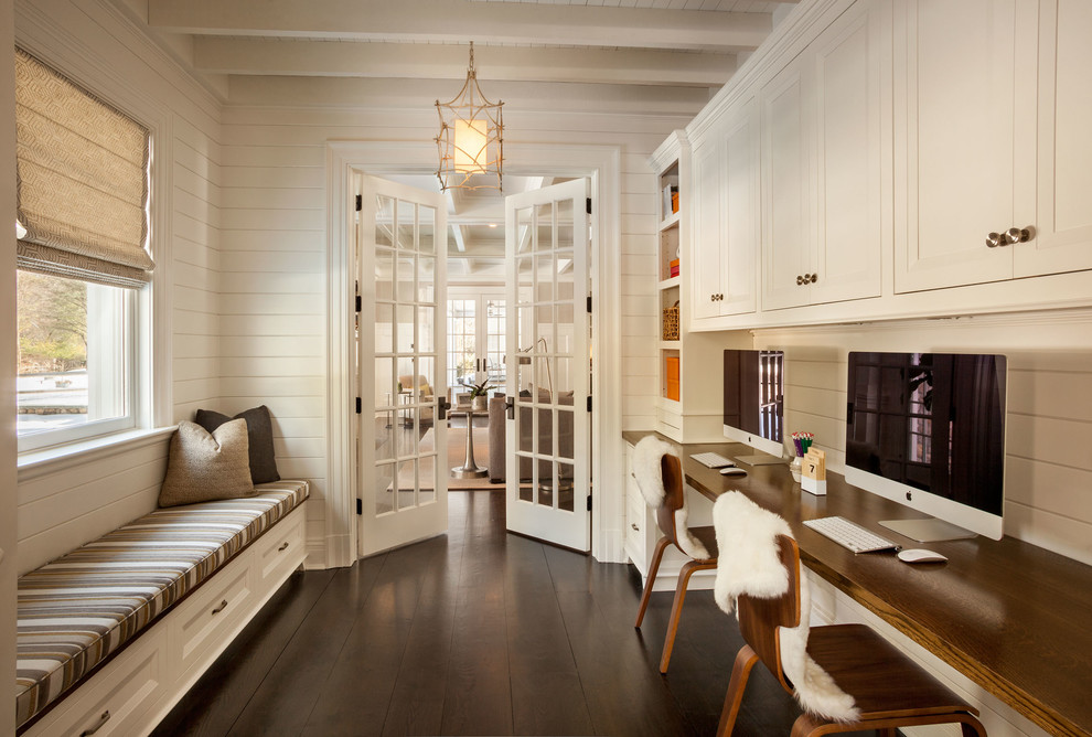 Mid-sized elegant built-in desk dark wood floor study room photo in New York with white walls