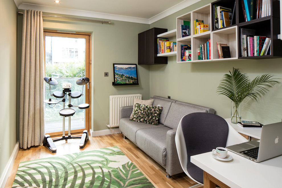 Inspiration for a small contemporary study in Dublin with green walls, medium hardwood flooring and a built-in desk.