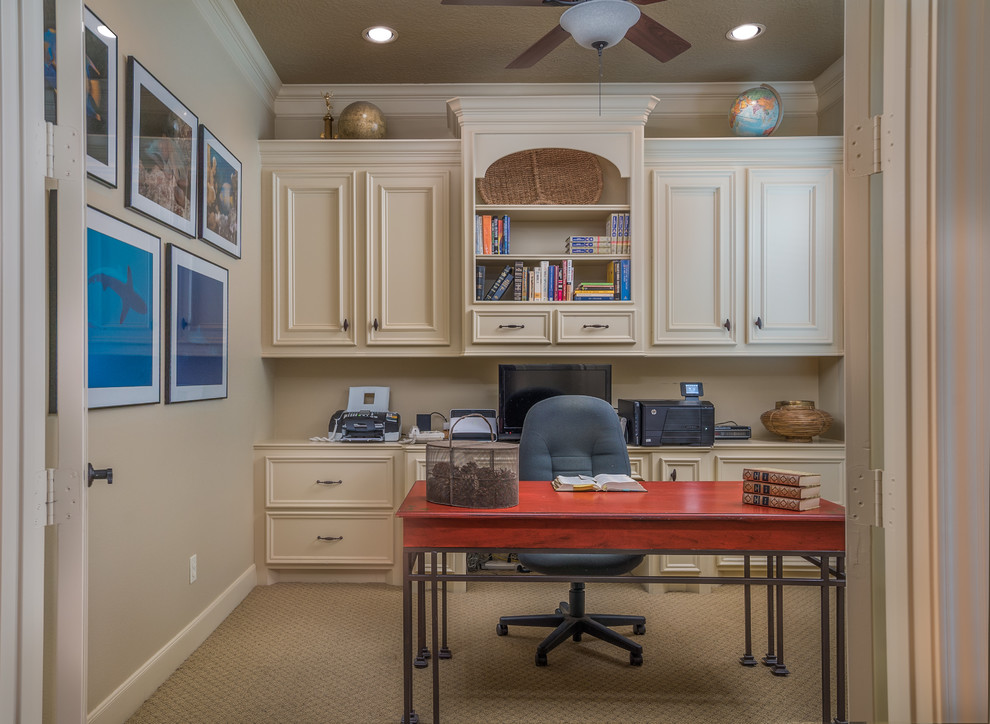 Klassisches Arbeitszimmer ohne Kamin mit Arbeitsplatz, beiger Wandfarbe, Teppichboden und freistehendem Schreibtisch in Houston