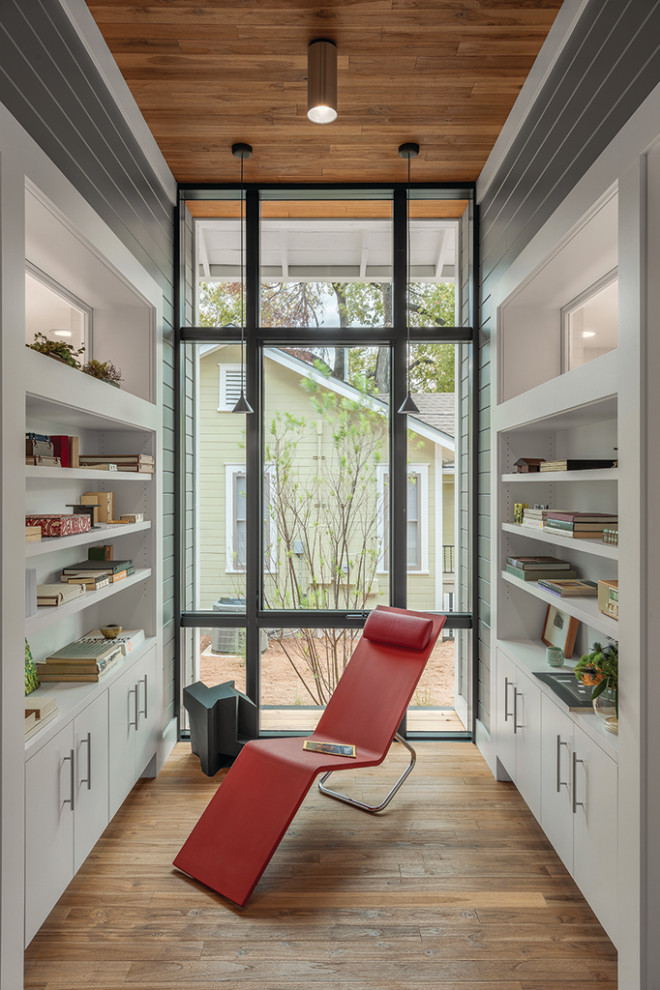 Kleines Modernes Arbeitszimmer mit Arbeitsplatz, weißer Wandfarbe, braunem Holzboden, freistehendem Schreibtisch und braunem Boden in Austin