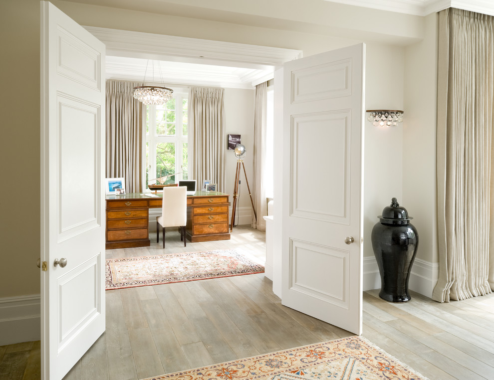 Klassisches Arbeitszimmer mit beiger Wandfarbe, hellem Holzboden, Arbeitsplatz, freistehendem Schreibtisch und beigem Boden in London