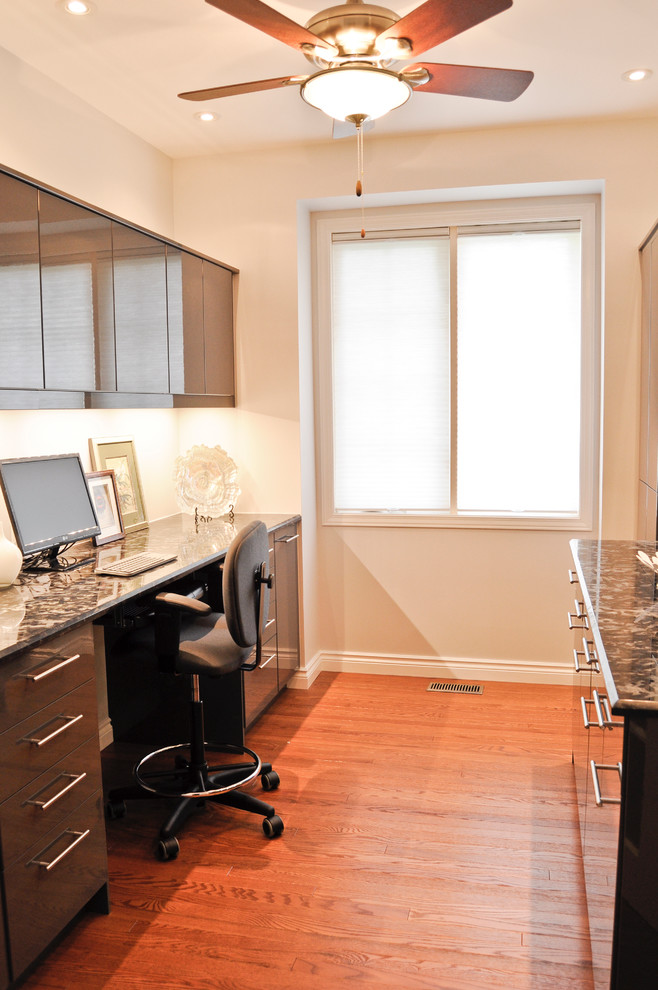 Modelo de despacho actual pequeño con paredes grises, suelo de madera en tonos medios y escritorio empotrado