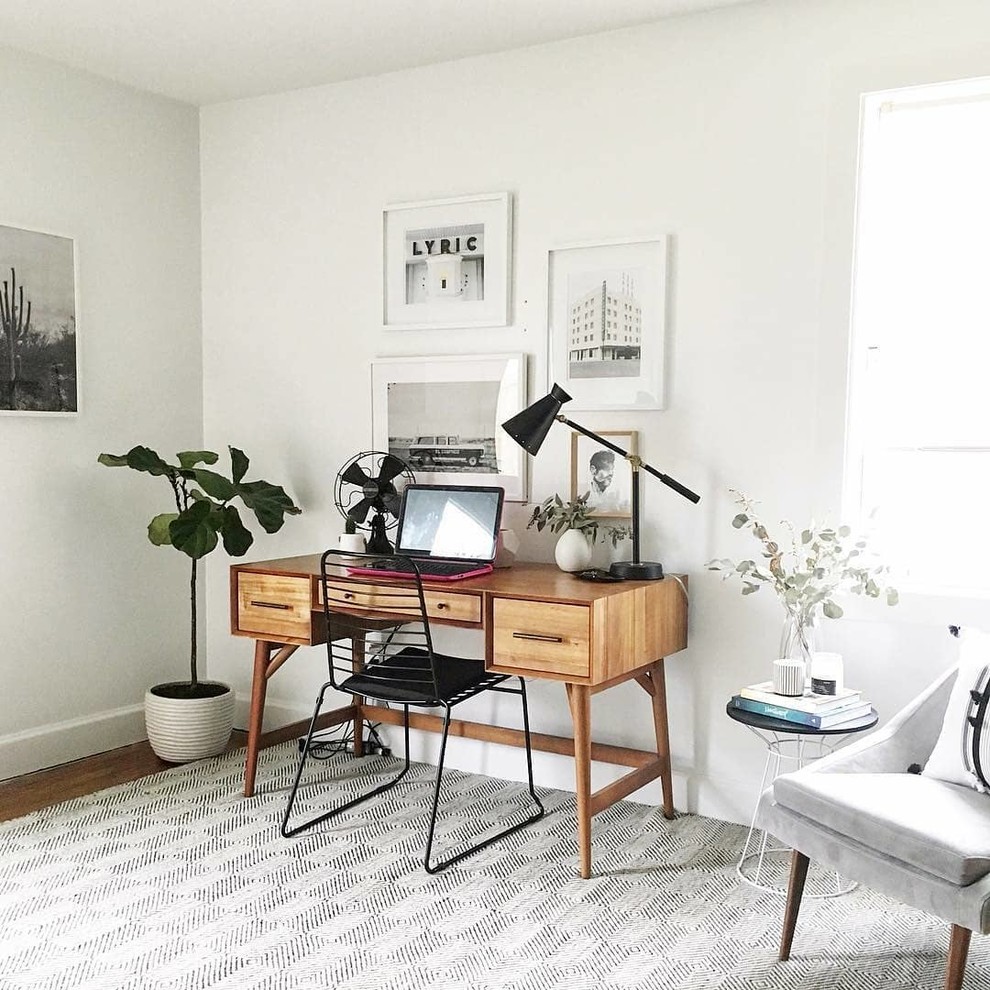 Immagine di uno studio minimal con pareti bianche, pavimento in legno massello medio, scrivania autoportante e pavimento marrone