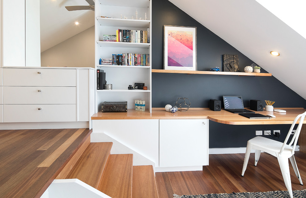 シドニーにあるコンテンポラリースタイルのおしゃれなホームオフィス・書斎 (黒い壁、ラミネートの床、暖炉なし、造り付け机、茶色い床) の写真