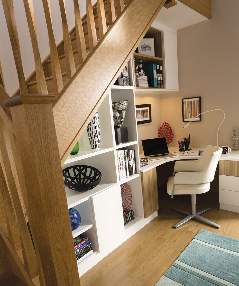 Aménagement d'un petit bureau contemporain avec un mur blanc, un sol en bois brun, un bureau intégré et un sol marron.
