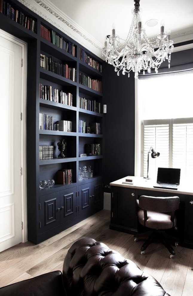 This is an example of a medium sized classic study in London with blue walls, medium hardwood flooring, a standard fireplace, a stone fireplace surround, a freestanding desk and brown floors.