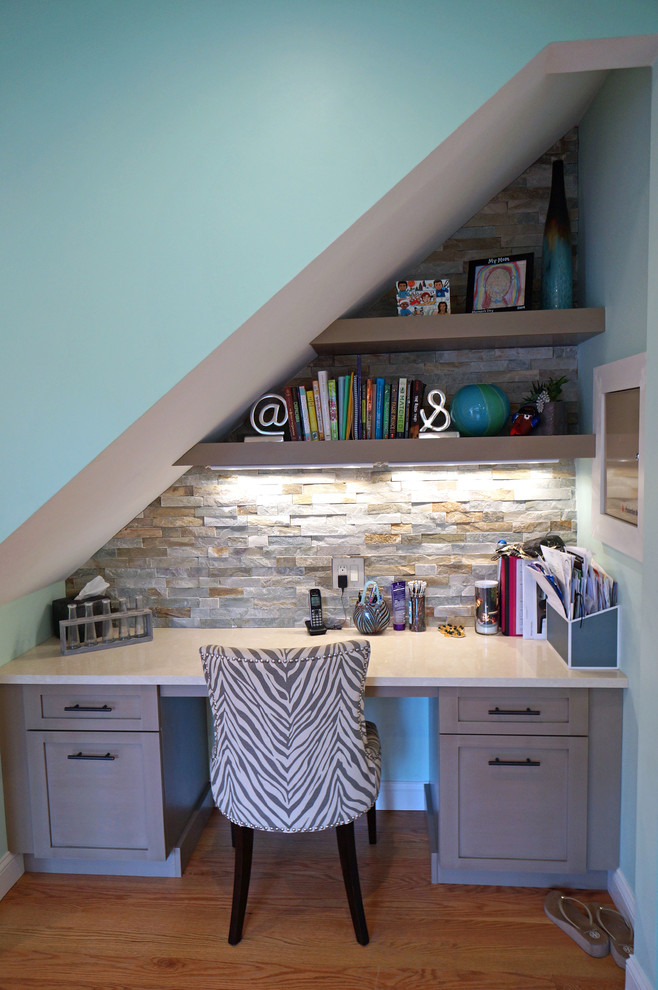 Modelo de despacho ecléctico pequeño sin chimenea con paredes azules, suelo de madera oscura y escritorio empotrado