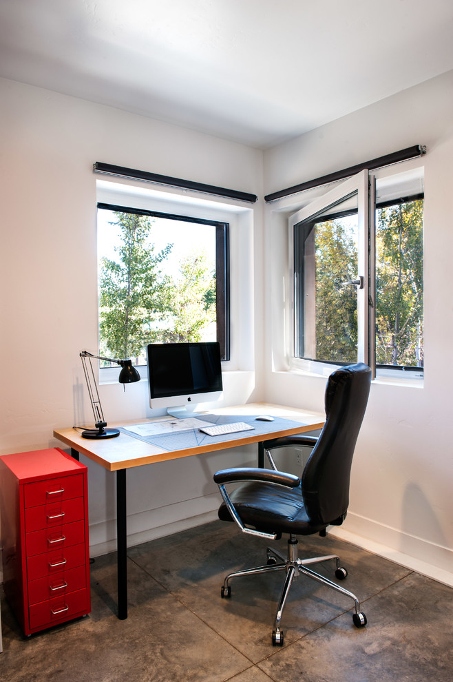 Esempio di un ufficio moderno con pareti bianche, pavimento in cemento, scrivania autoportante e pavimento grigio