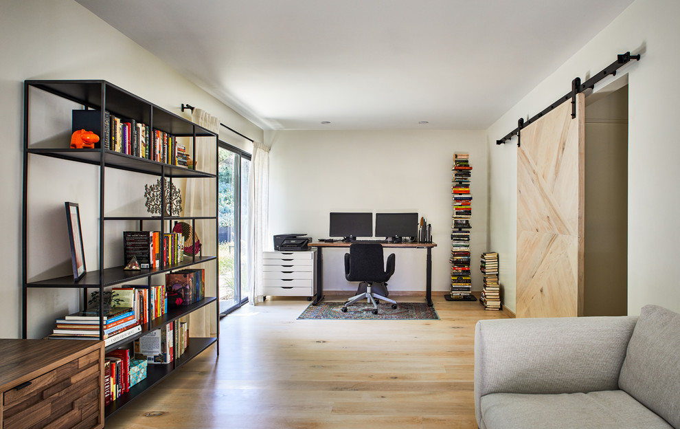 Imagen de despacho escandinavo de tamaño medio con paredes blancas, suelo de madera clara, escritorio independiente y suelo beige